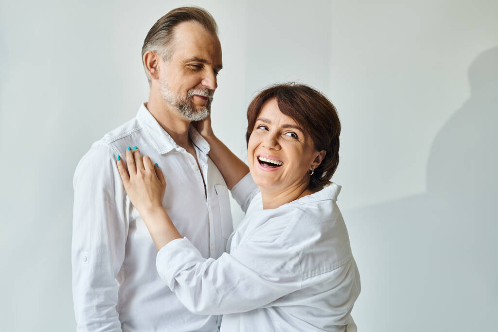 Mature beautiful couple in love standing on grey background and laughing to camera - Photo, Image
