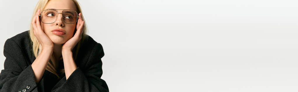 elegante mujer joven con el pelo rubio y gafas elegantes en el abrigo negro posando y mirando hacia otro lado, pancarta - Foto, imagen