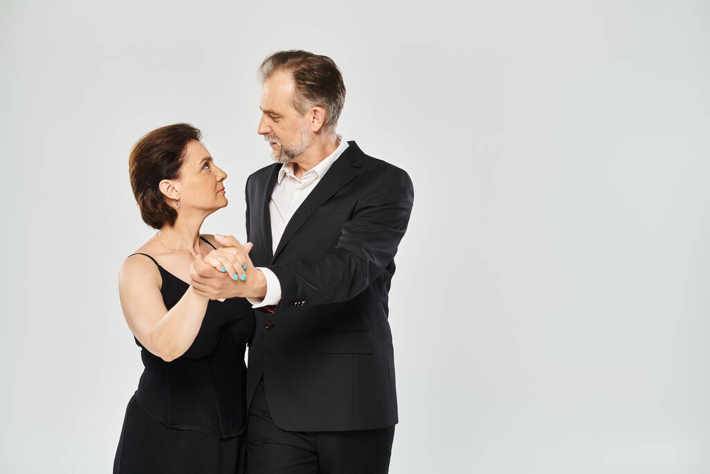 Бальний танець середнього віку пара в танцювальній позі і посміхається ізольовано на сірому фоні - Фото, зображення