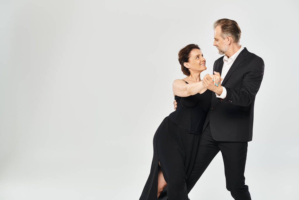 Ballroom tanssi keski-ikäinen pari tanssi aiheuttaa ja hymyilee eristetty harmaalla pohjalla - Valokuva, kuva