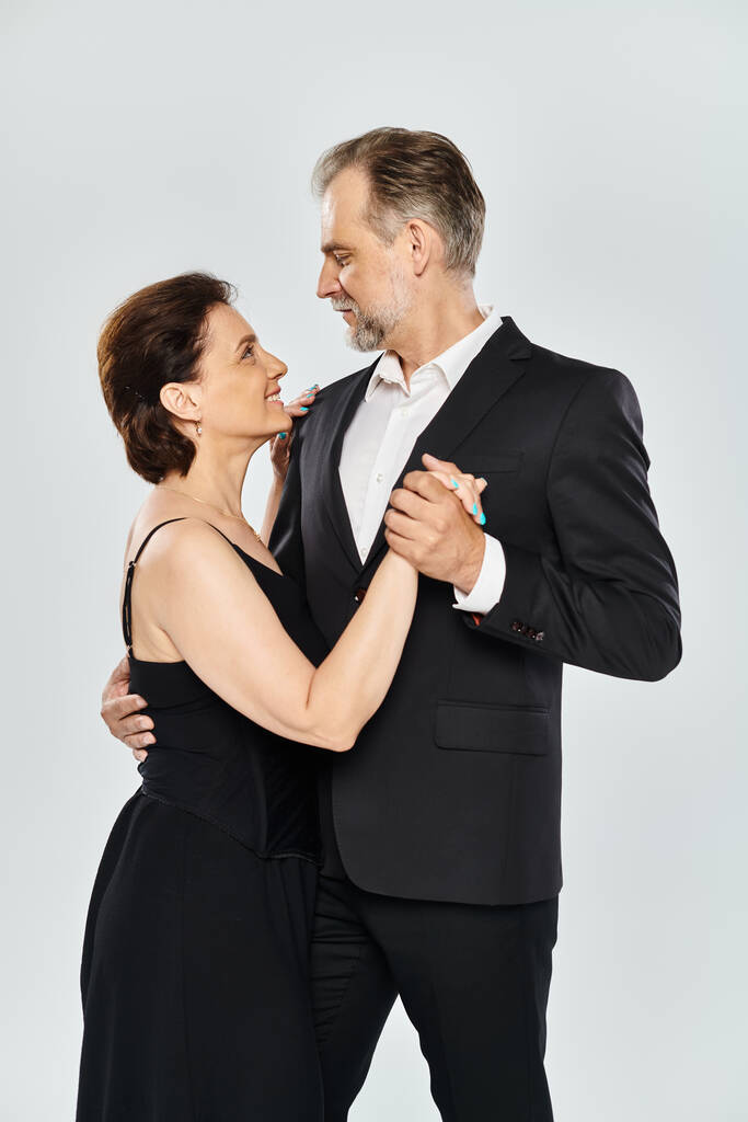 Снимок зрелой привлекательной пары в танцевальной позе танго, изолированной на сером фоне - Фото, изображение