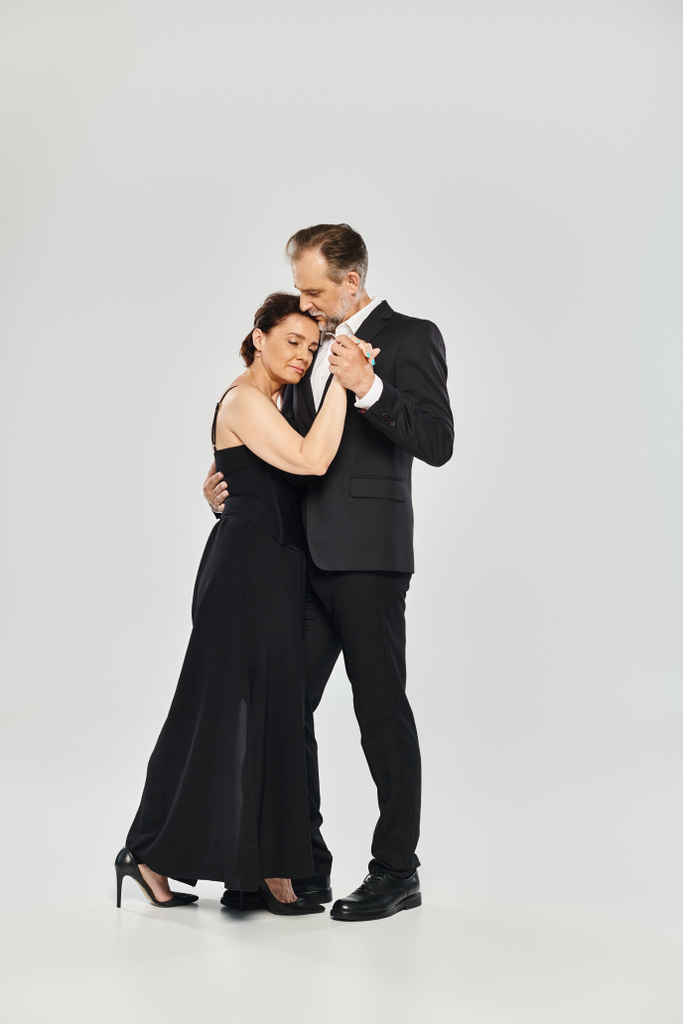 Foto completa de pareja atractiva madura en una pose de baile de tango aislada sobre fondo gris - Foto, imagen