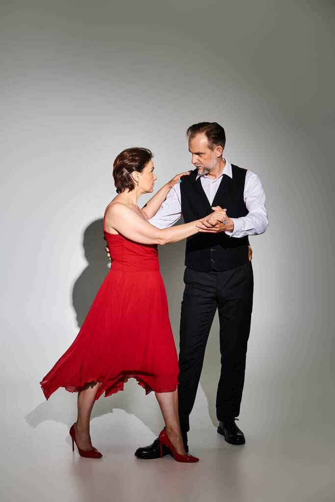 Ballroom dança casal de meia idade em vestido vermelho e terno dança tango isolado no fundo cinza - Foto, Imagem