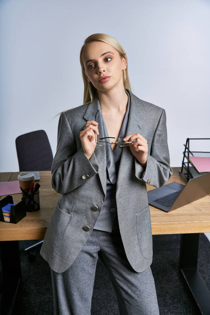mujer de negocios de buen aspecto de moda en traje gris sofisticado con cabello rubio mirando hacia otro lado - Foto, Imagen