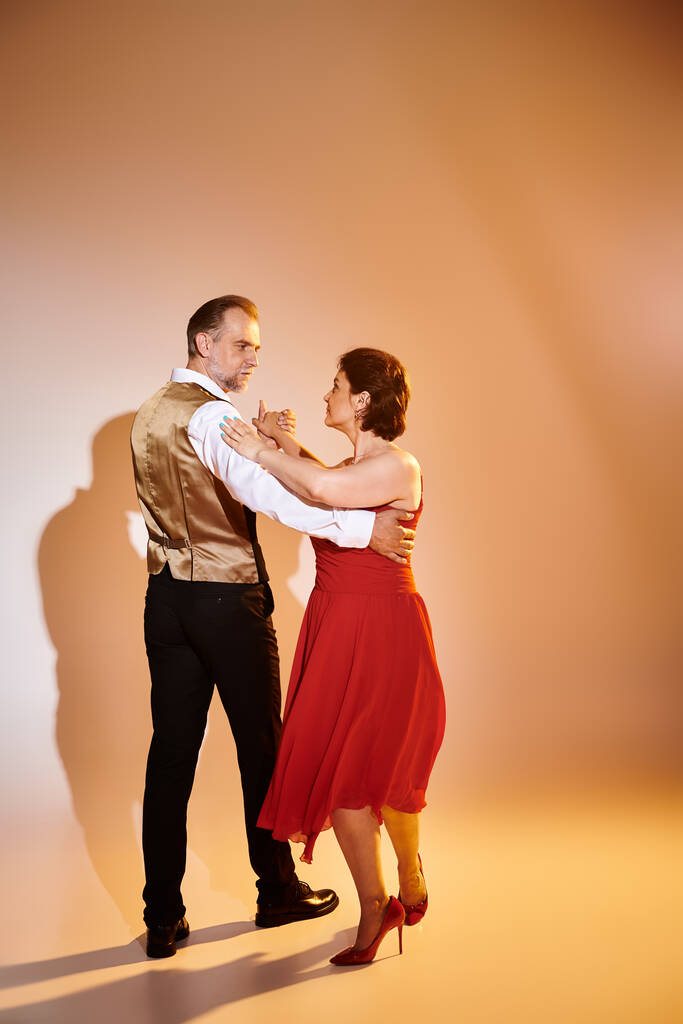 Ballroom tanssi keski-ikäinen pari punainen mekko ja puku tanssia tango keltainen valo harmaa - Valokuva, kuva