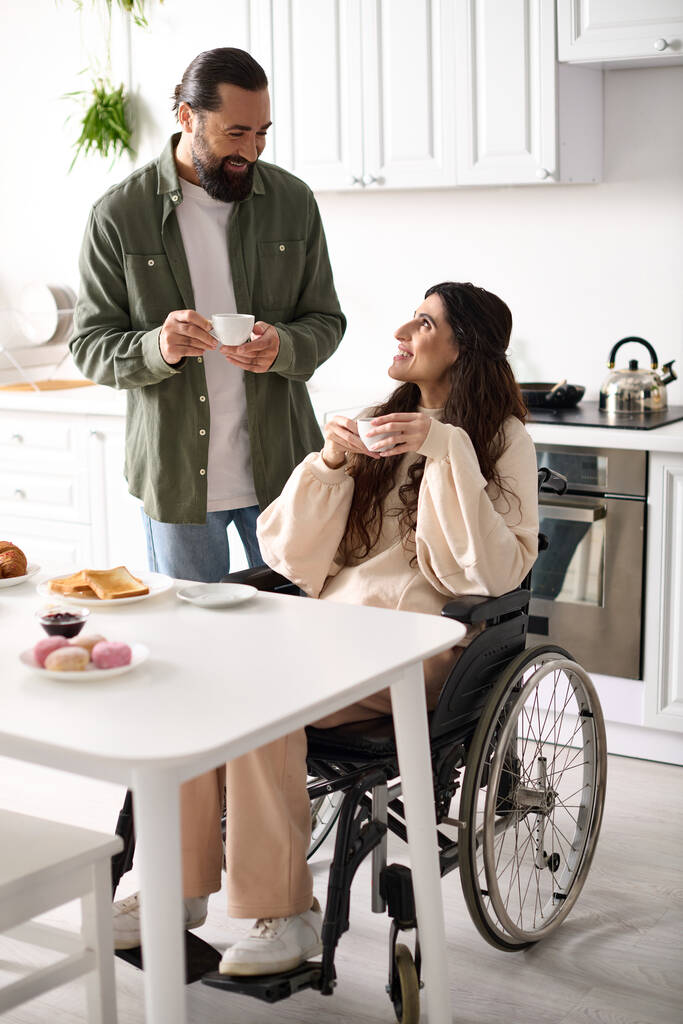 vidám gyönyörű mozgássérült nő tolószékben élvezi a kávét a férjével reggeli közben - Fotó, kép