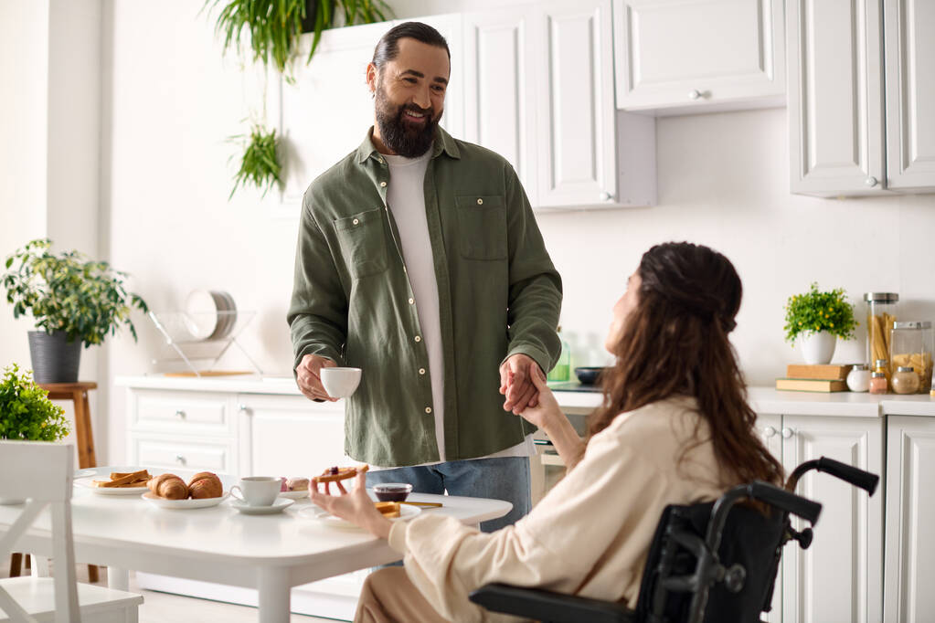 alegre atractiva mujer con discapacidad en silla de ruedas desayunando con su amado marido - Foto, Imagen