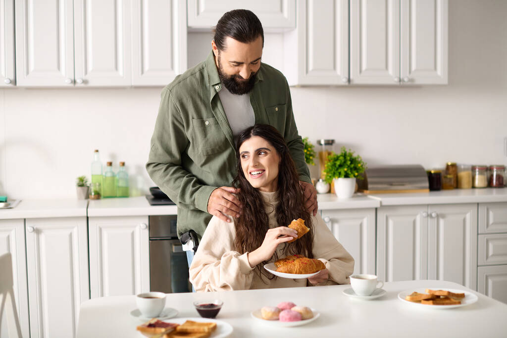クロワッサンを食べる彼の美しい障害のある妻と朝食で素晴らしい時間を過ごす肯定的な男 - 写真・画像