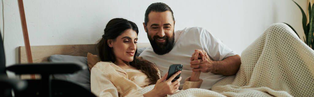 весела жінка з інвалідністю, лежачи в ліжку поруч з її бородатим люблячим чоловіком, банер - Фото, зображення