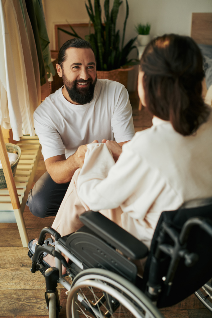 good looking cheerful man spending time with his beautiful disabled wife while in bedroom at home - Photo, Image