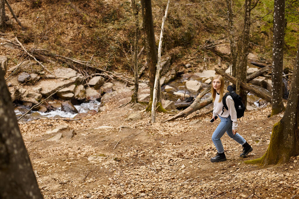 Caminhante loiro curioso com mochila de viagem, tecendo através da floresta olhando para o céu - Foto, Imagem