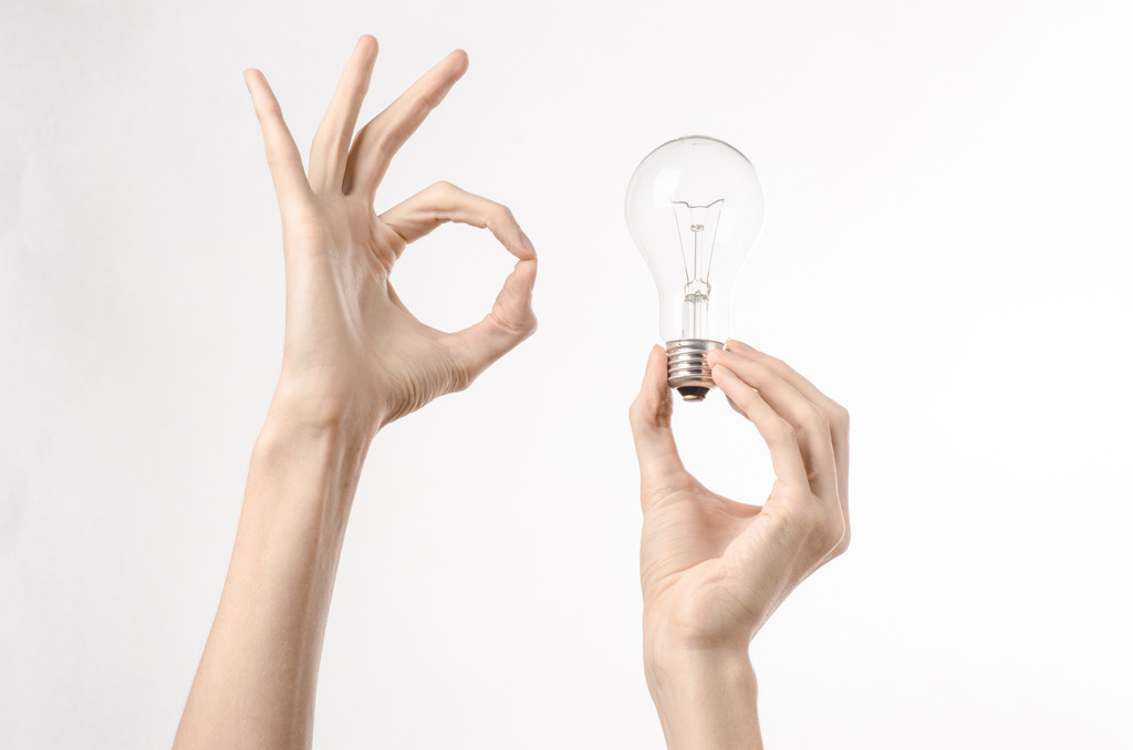 Consumo di energia e risparmio energetico argomento: mano umana tenendo una lampadina su sfondo bianco in studio
 - Foto, immagini