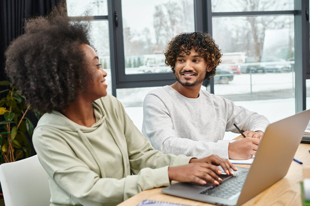 A multikulturális diákok együttműködésen alapuló tanulmányokat folytatnak egy asztalnál laptoppal egy modern coworking térben. - Fotó, kép