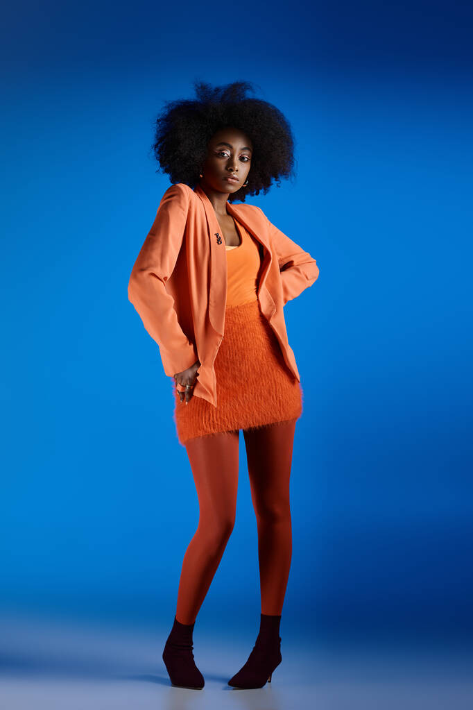 modelo americano Africano bonita em vestido texturizado e blazer posando com a mão no quadril em saltos altos - Foto, Imagem