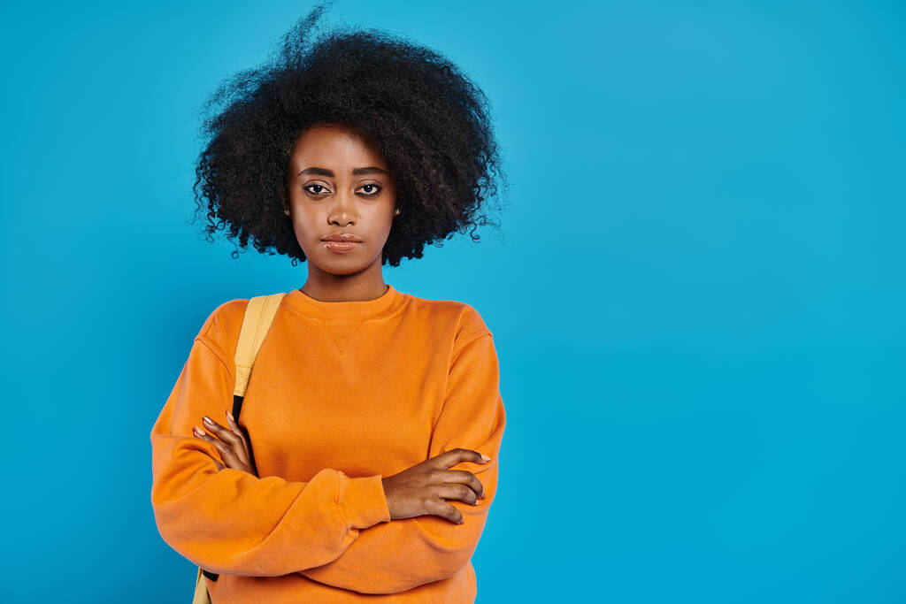Стильная афроамериканка с огромным афро уверенно стоит на ярком синем фоне. - Фото, изображение