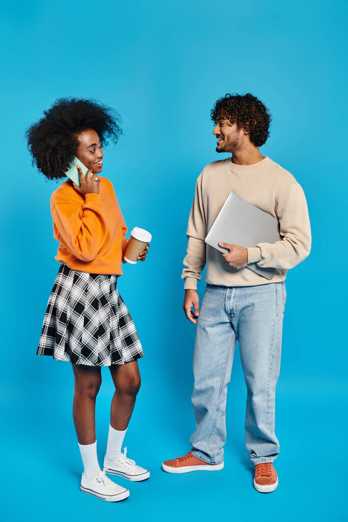 Мужчина и женщина, межрасовые студенты, стоят бок о бок в повседневной одежде на синем фоне. - Фото, изображение
