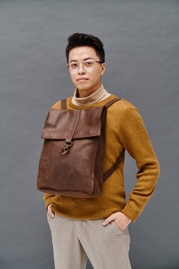 Ein modischer junger Mann in eleganter Kleidung trägt einen braunen Rucksack - Foto, Bild