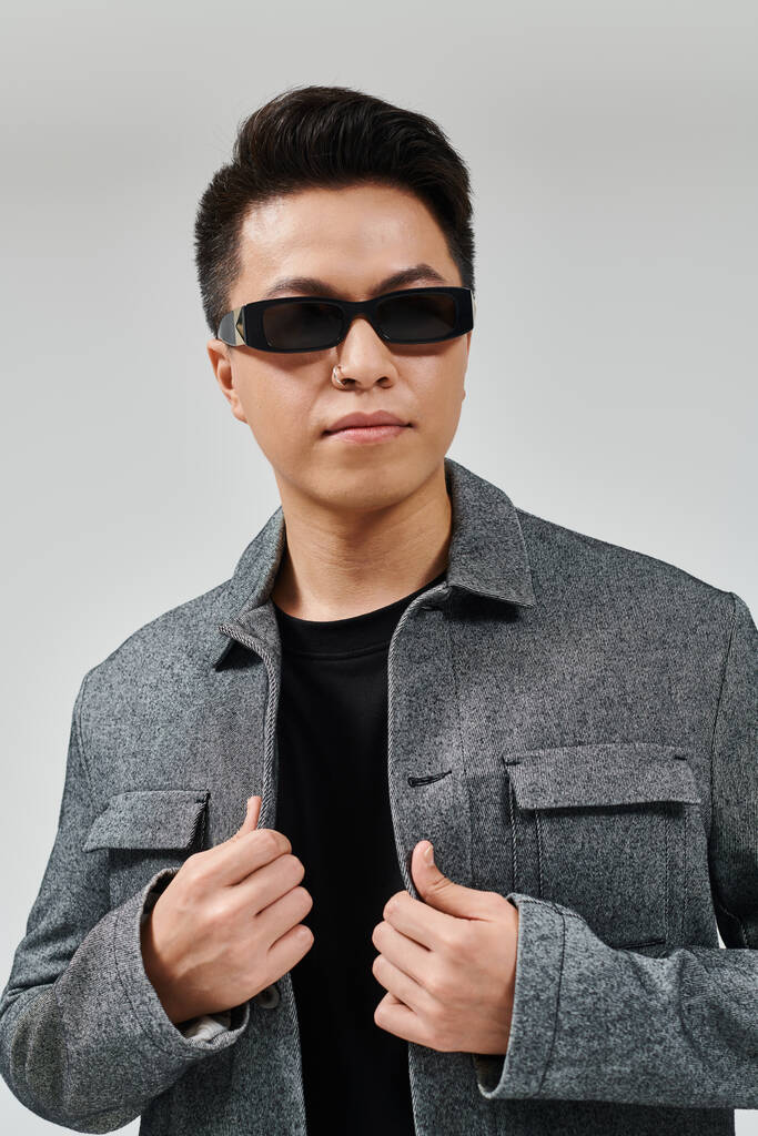Egy divatos fiatalember, aki magabiztosan pózol napszemüvegben és elegáns dzsekiben.. - Fotó, kép