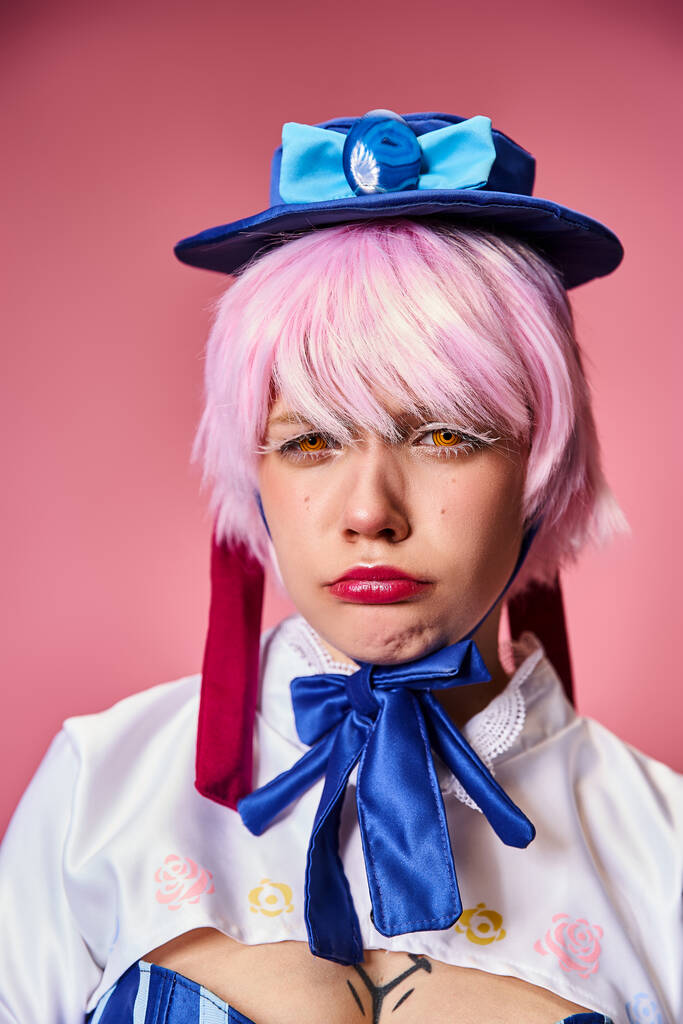 appealing young female cosplayer with red gloves and blue hat posing emotionally on pink backdrop - Photo, Image