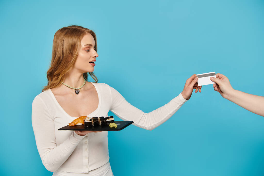 Una donna bionda che consegna un biglietto ad un'altra donna, entrambe impegnate in uno scambio amichevole sulla deliziosa cucina asiatica. - Foto, immagini