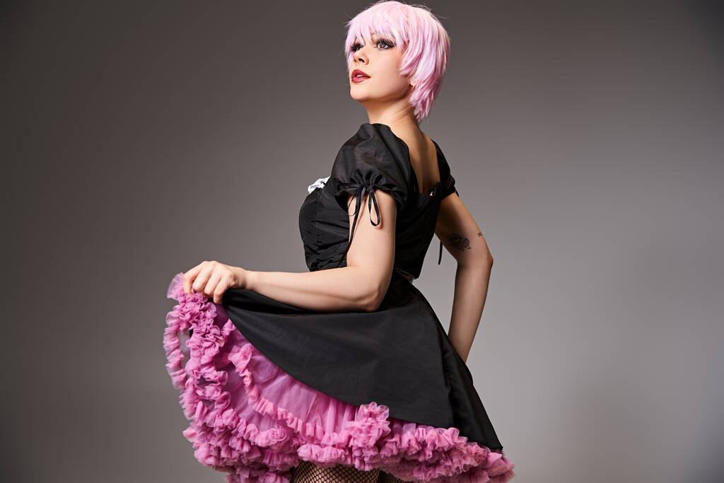 Привлекательная женщина, играющая сексуальную аниме-героиню с розовыми волосами и отводящая взгляд на заднем плане - Фото, изображение