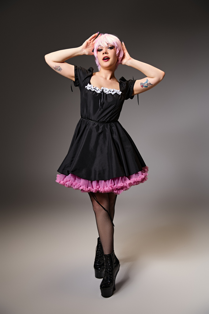 vonzó elegáns nő fekete ruhában rózsaszín hajjal cosplaying anime karakter és a kamera - Fotó, kép