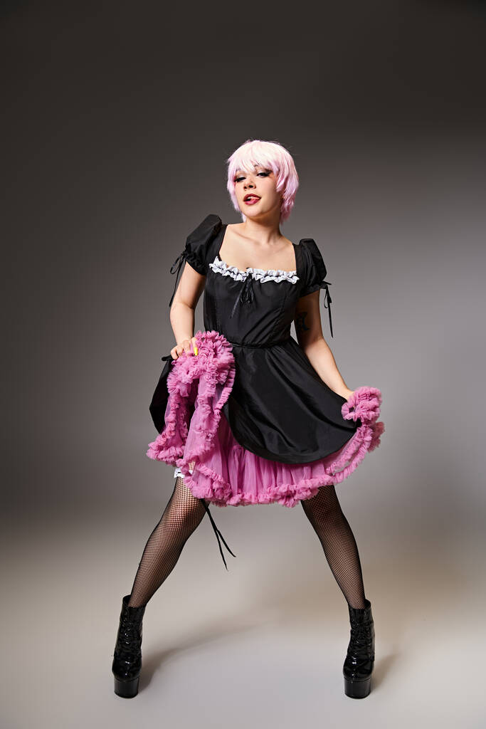 jolly female cosplayer in sexy maid costume with pink hair sticking her tongue and looking at camera - Photo, Image