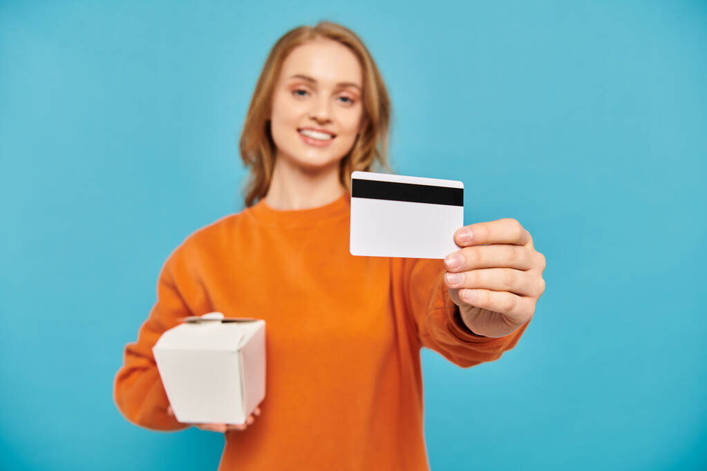 Una donna elegante detiene una carta di credito e una scatola, in mostra uno stile di vita moderno e consumismo. - Foto, immagini