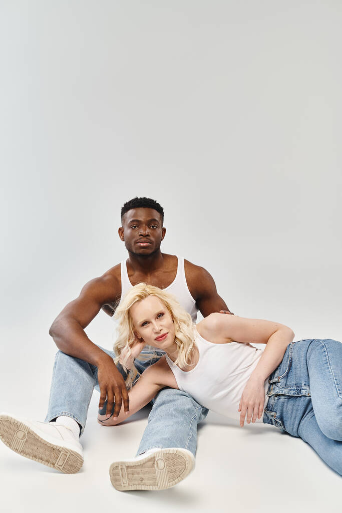 Un homme et une femme, jeunes et multiculturelles, posent gracieusement pour un portrait dans un studio sur fond gris. - Photo, image