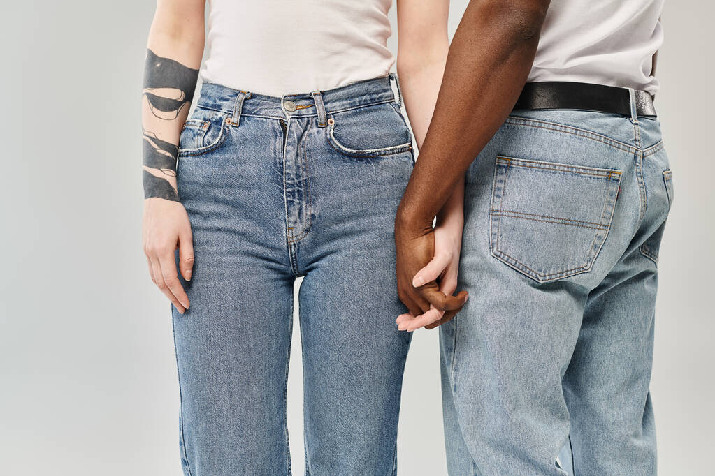 Un jeune couple multiculturel debout l'un à côté de l'autre dans un studio sur fond gris. - Photo, image