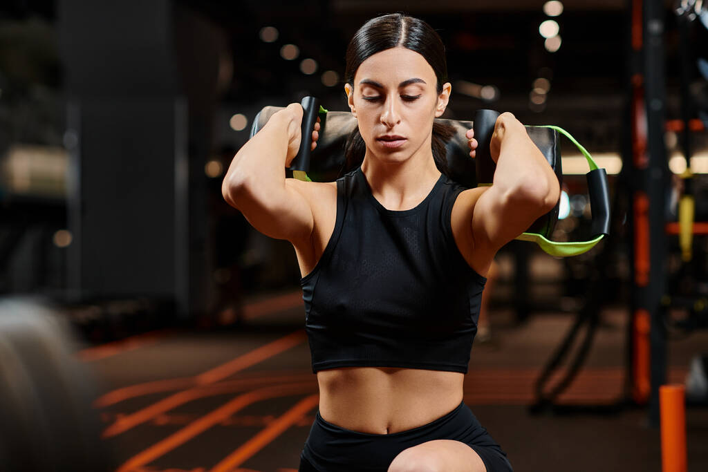 atractiva mujer atlética con cabello moreno en ropa deportiva haciendo ejercicio activamente con bolsa de energía en el gimnasio - Foto, Imagen