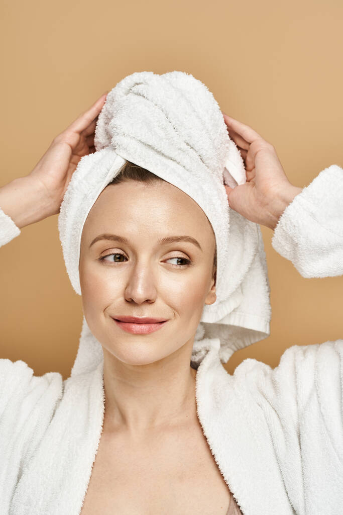 Una mujer con una toalla envuelta alrededor de su cabeza, exudando elegancia y tranquilidad. - Foto, Imagen