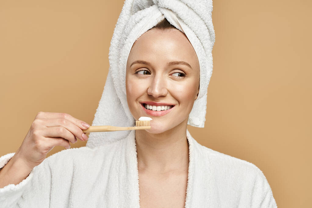 Une jolie femme avec une serviette sur la tête se brosse les dents dans une routine quotidienne du matin. - Photo, image
