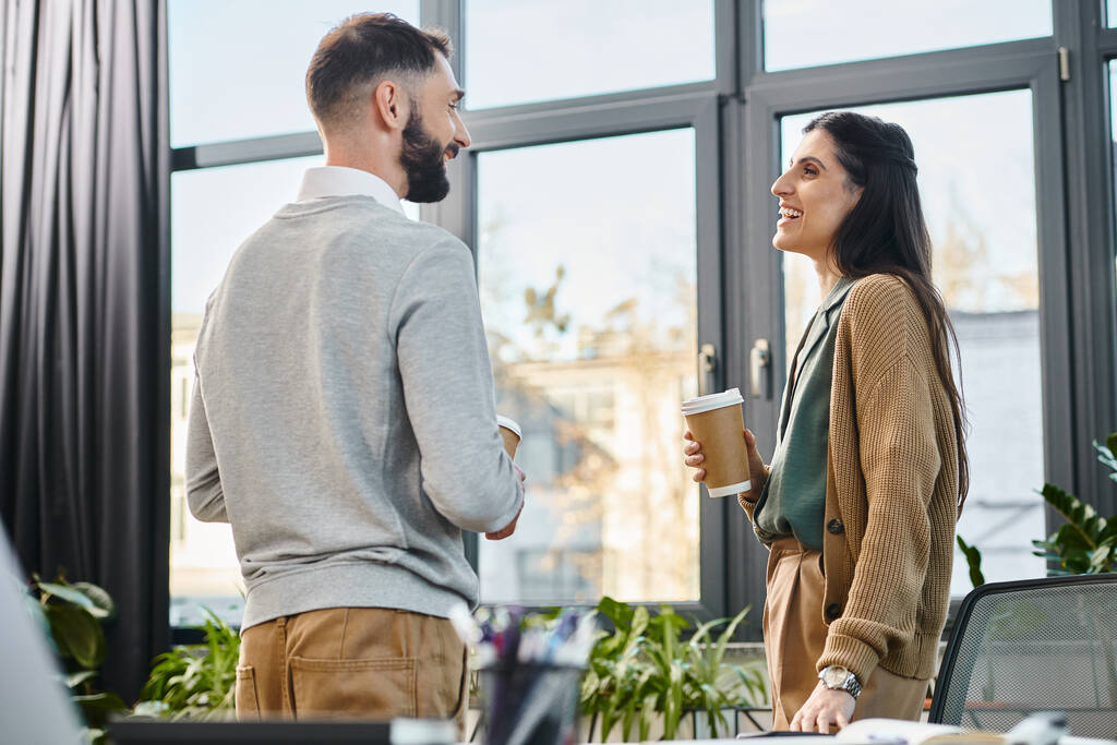 Ein Mann und eine Frau führen eine lebhafte Diskussion in einem modernen Büroumfeld, das die Essenz der Teamarbeit in der Unternehmenskultur widerspiegelt. - Foto, Bild