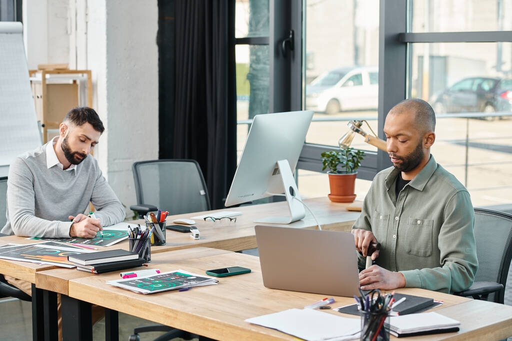 Dois empresários sentam-se à mesa, imersos em seus laptops, fazendo brainstorming e colaborando em um projeto em um ambiente de escritório moderno, inclusive - Foto, Imagem