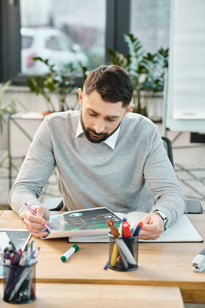 Un hombre absorto en el trabajo mientras está sentado en una mesa con una tableta en un entorno de oficina corporativa. - Foto, imagen