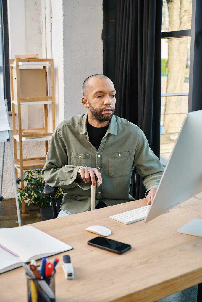 Niepełnosprawny Afroamerykanin z miastenią w stroju biznesowym siedzi dokładnie przed laptopem, skupiony na projekcie kultury korporacyjnej i produktywności. - Zdjęcie, obraz