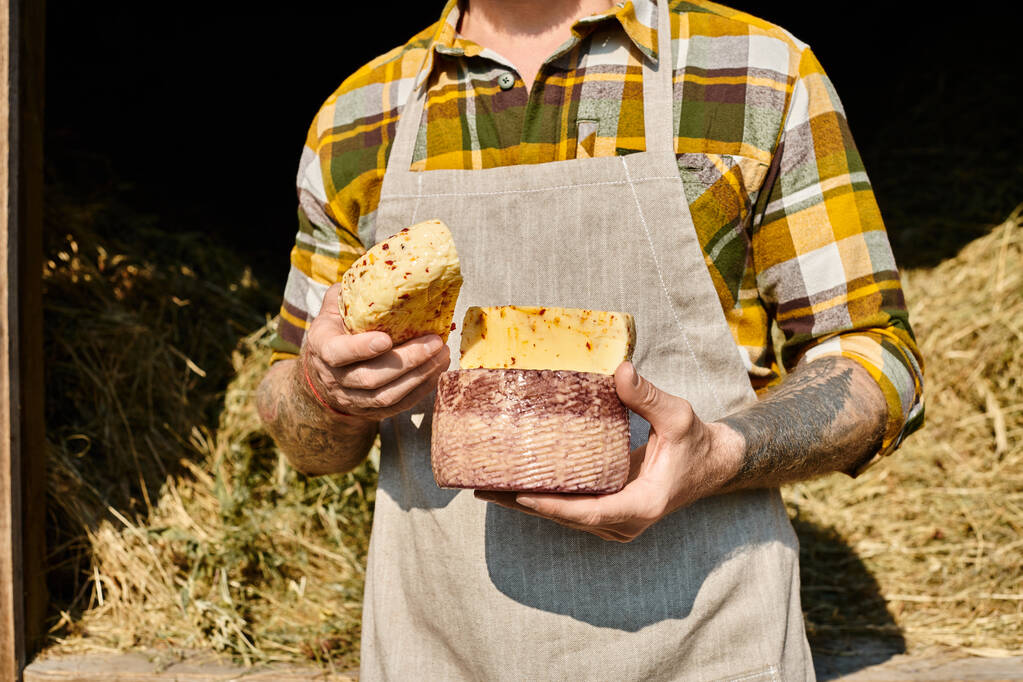 cropped view of adult farmer with tattoos in casual attire holding homemade cheese in hands - Photo, Image
