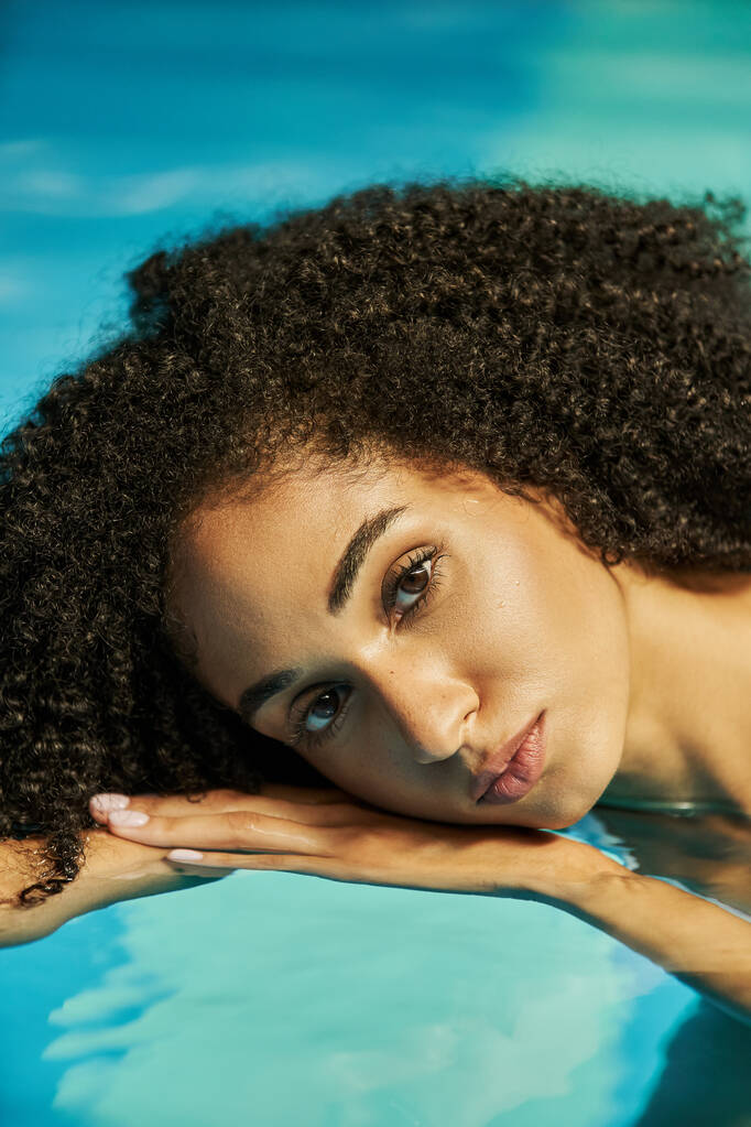 portré fiatal afro-amerikai nő göndör haj néz kamera és úszás a vízben - Fotó, kép