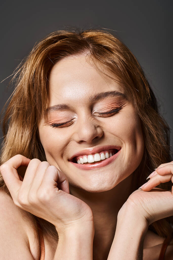 Schönheitsporträt einer attraktiven lachenden jungen Frau, die ihr Gesicht berührt und im Studio posiert - Foto, Bild