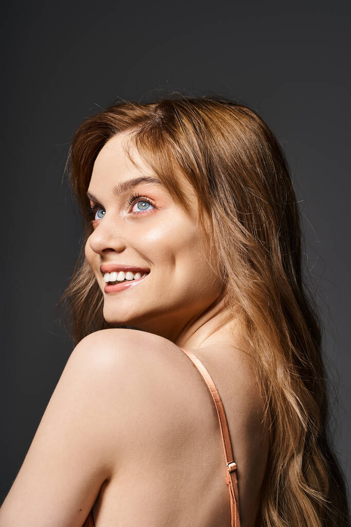 Πλάτη άποψη πορτρέτο του χαρούμενα χαμογελαστή νεαρή γυναίκα με μπλε μάτια, ποζάρουν σε σκούρο γκρι φόντο - Φωτογραφία, εικόνα