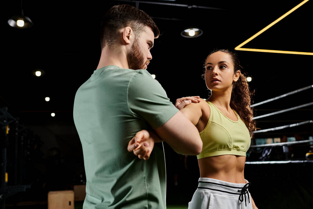 Een mannelijke trainer demonstreert zelfverdedigingstechnieken voor een vrouw in een fitnessruimte. - Foto, afbeelding