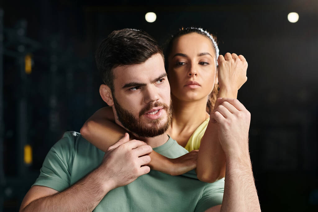 Ein Mann, ein Selbstverteidigungstrainer, hält eine Frau auf dem Arm und demonstriert eine Technik in einem Fitnessstudio. - Foto, Bild