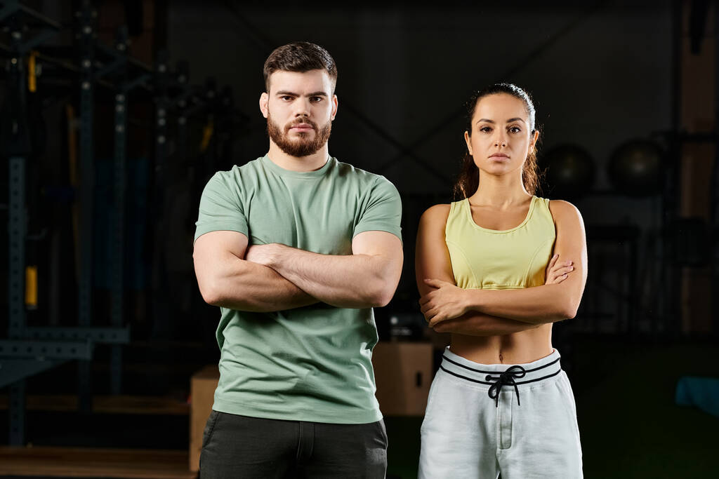 Een mannelijke trainer die zelfverdedigingstechnieken leert aan een vrouw in een sportschool, die beiden vol vertrouwen naast elkaar staan.. - Foto, afbeelding