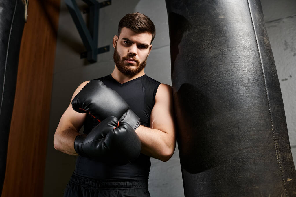 Handsome bearded man in gym, throwing punches at punching bag with determination and focus. - Photo, Image
