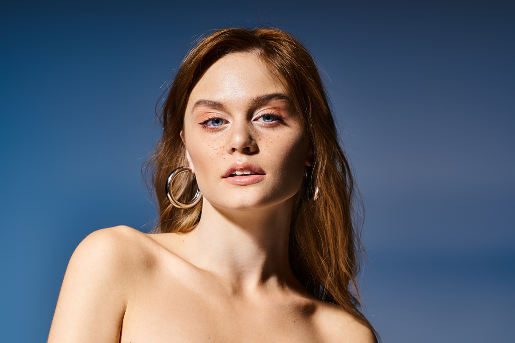 Beauty portret van mooie jonge vrouw met natuurlijke make-up, kijken naar camera op blauwe achtergrond - Foto, afbeelding