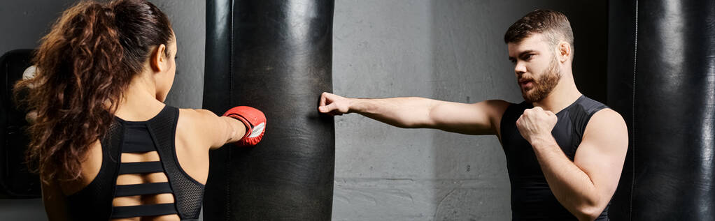 Een mannelijke trainer begeleidt een brunette sporter in actieve kleding door middel van boksoefeningen in een fitnessruimte. - Foto, afbeelding