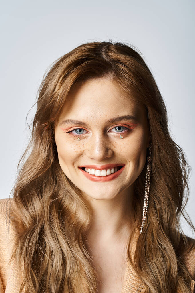 Krása portrét usmívající se mladé ženy s obličejem šperky make-up na šedém pozadí - Fotografie, Obrázek