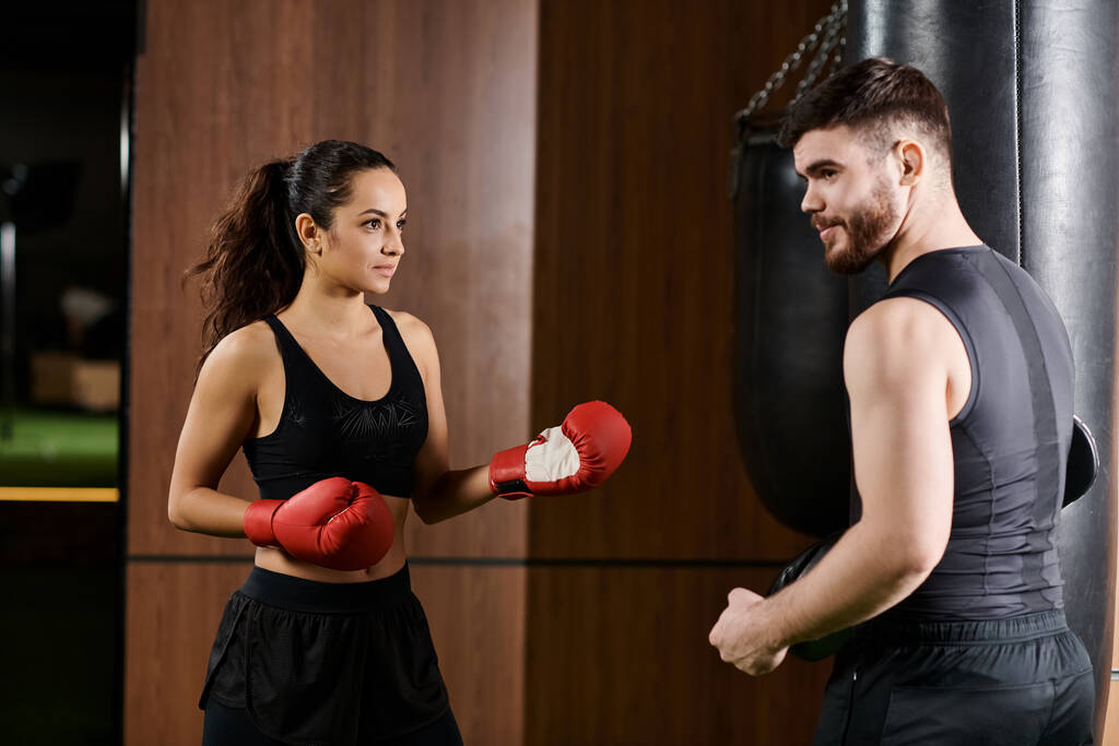 Тренер-мужчина тренирует брюнетку-спортсменку в боксёрских перчатках в спортзале. - Фото, изображение