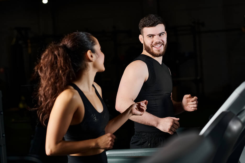 Ein Personal Trainer steht neben einer brünetten Sportlerin in einem Fitnessstudio, bereit für eine Trainingseinheit. - Foto, Bild